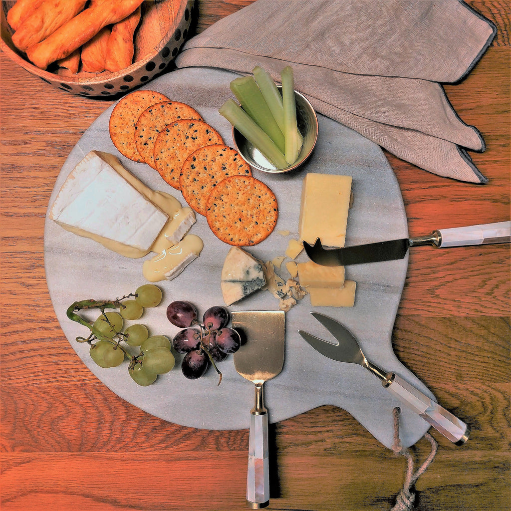 a Megha Round Marble Cheese / Chopping Board with cheese, crackers and grapes.